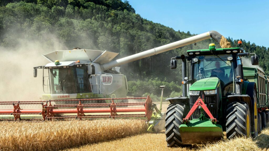 Combine harvester and tractor working together in a wheat field during summer.